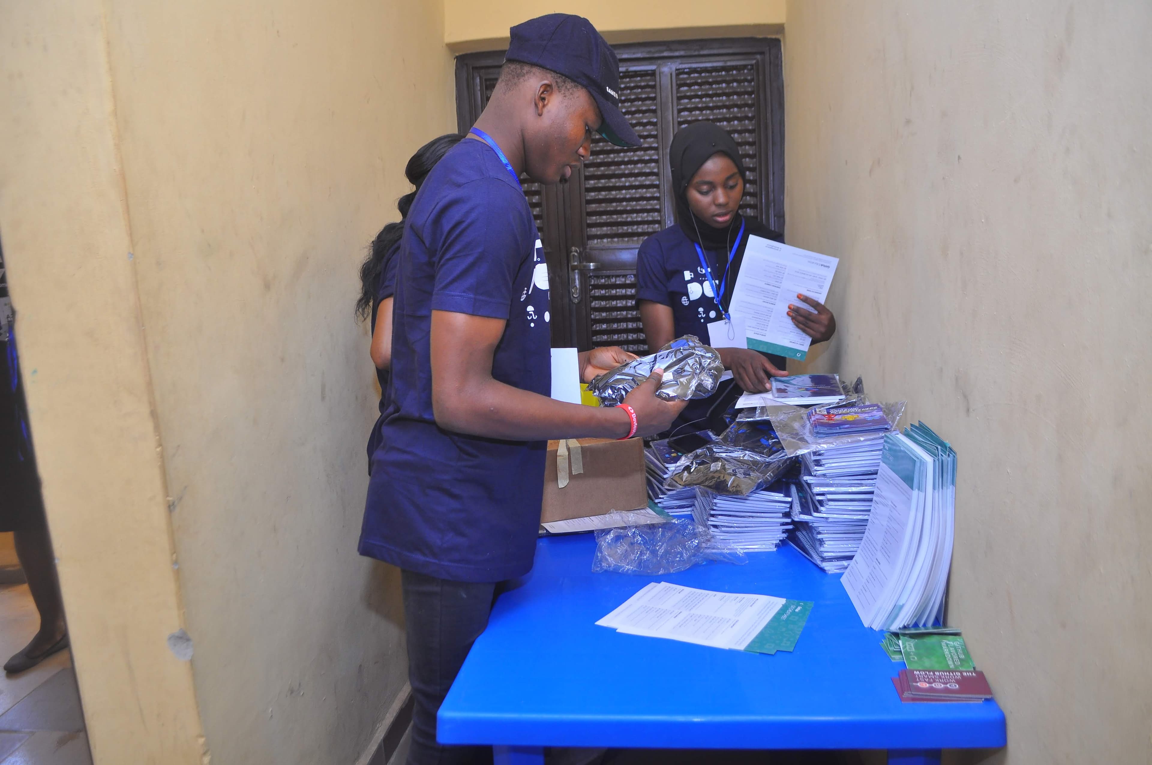 People in DevFest T-shirts sorting materials at a table at DevFest Ogbomoso 2019