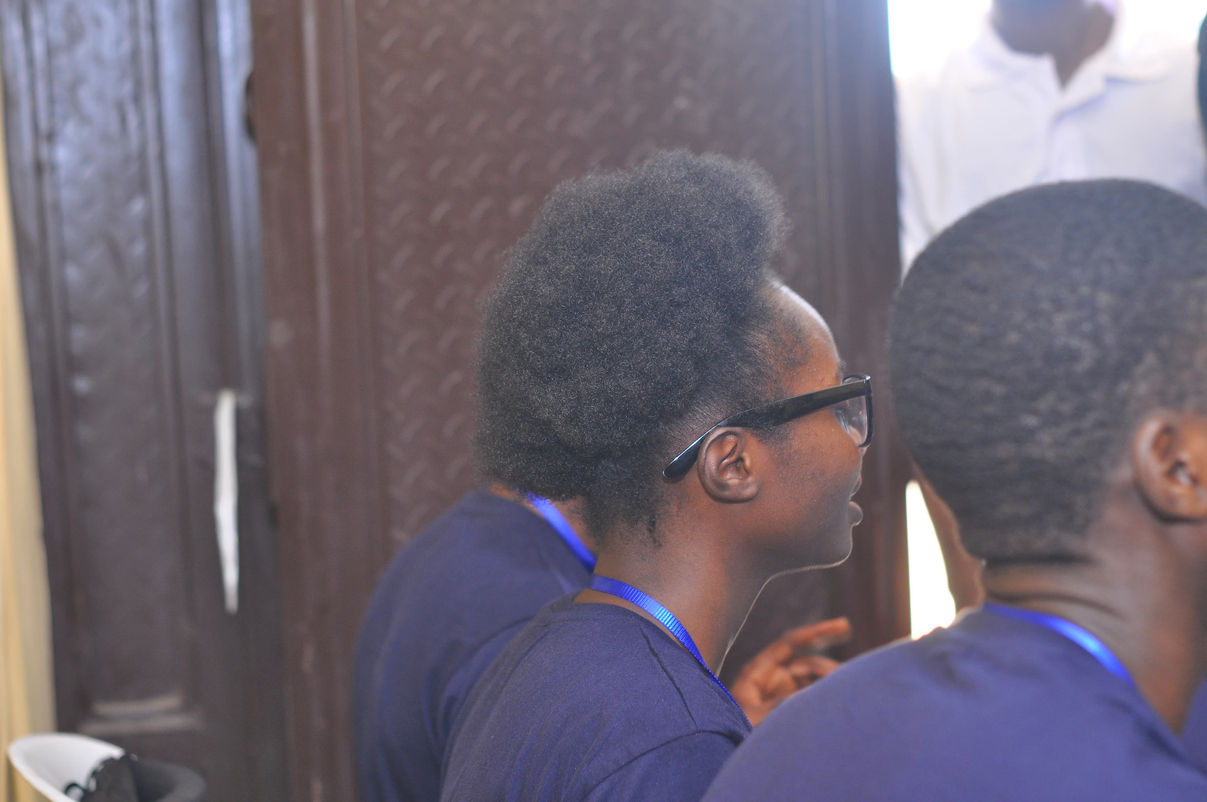 Attendees with lanyards beside a wooden door at DevFest Ogbomoso 2019