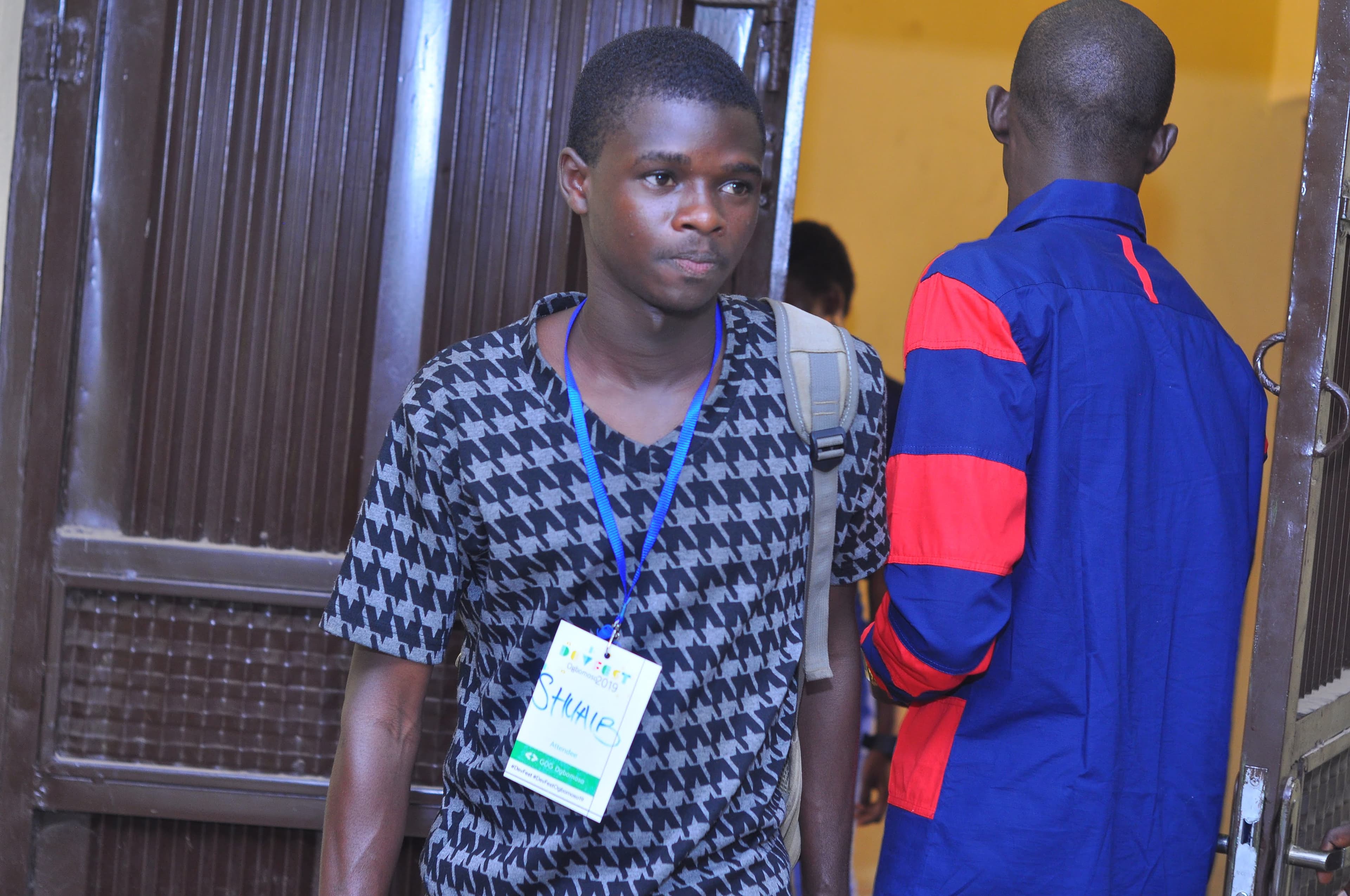 An attendee with a backpack wearing a conference badge at DevFest Ogbomoso 2019