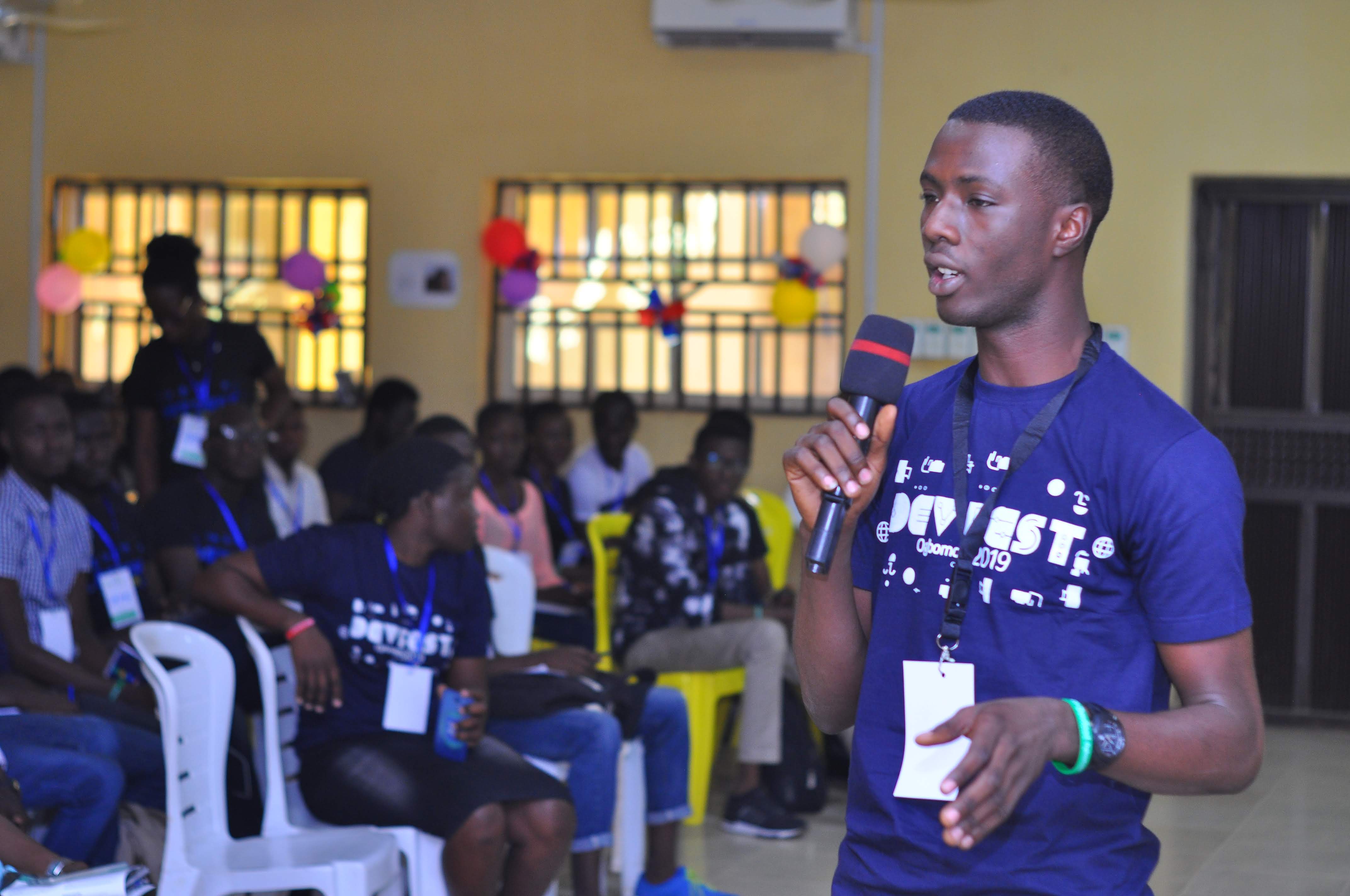 An attendee speaking into a microphone near seated attendees at DevFest Ogbomoso 2019