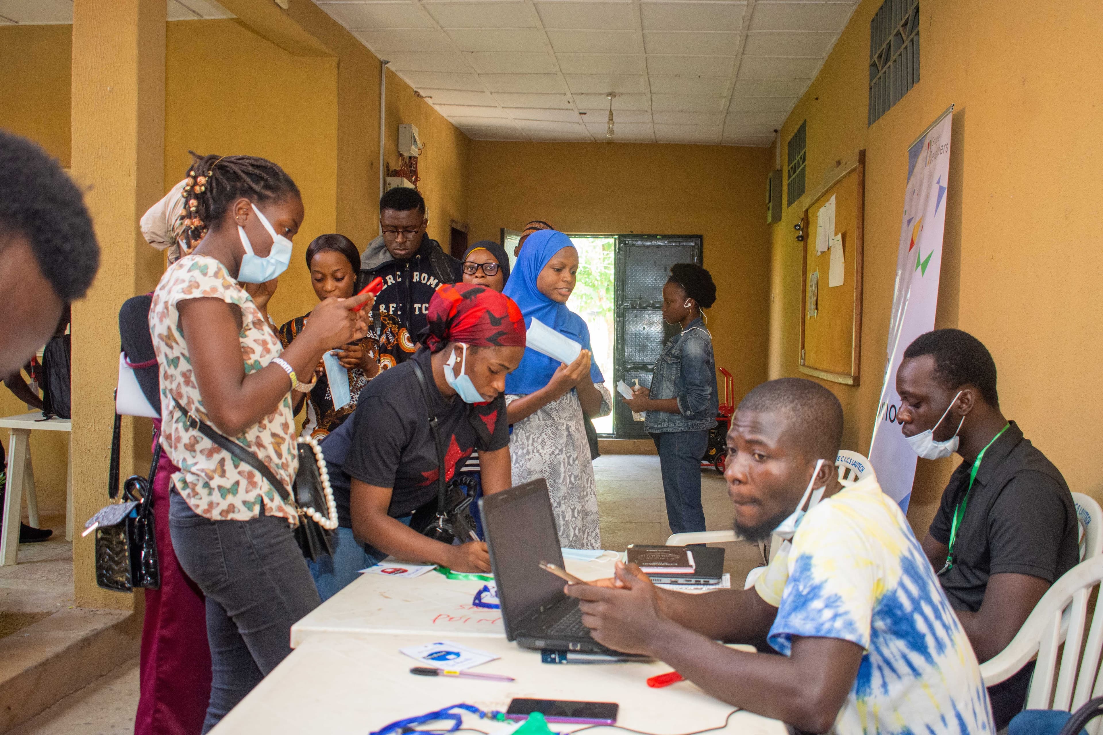 Attendees queuing at a table with a laptop at DevFest Ogbomoso 2021