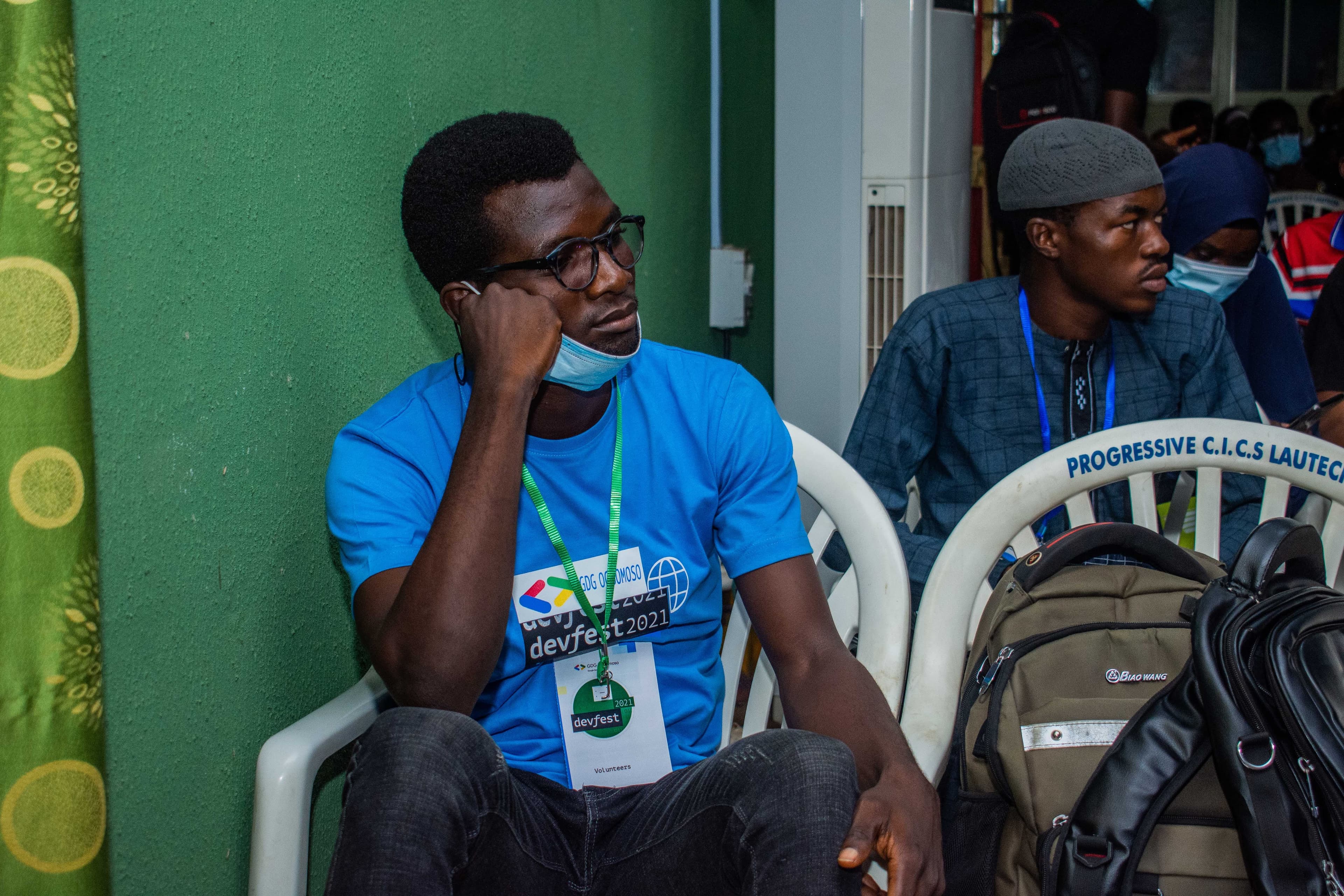 Two seated attendees near a green wall at DevFest Ogbomoso 2021