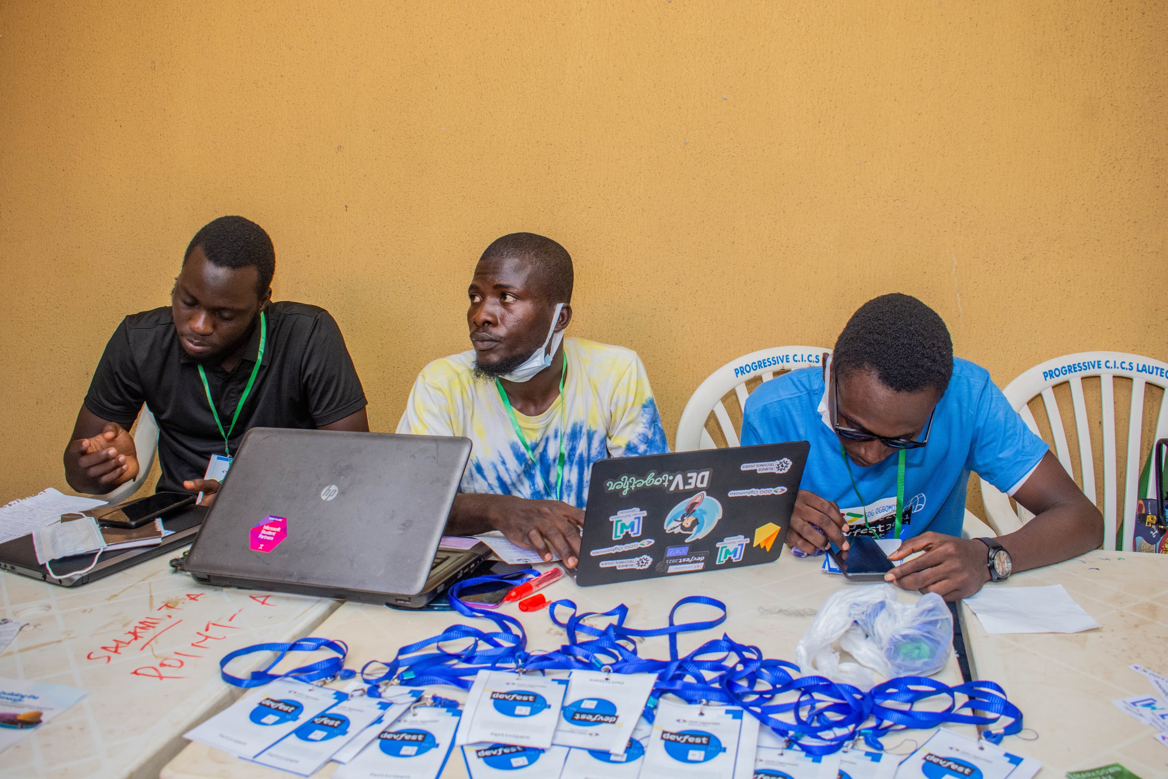 Three people at a table with laptops and DevFest badges at DevFest Ogbomoso 2021