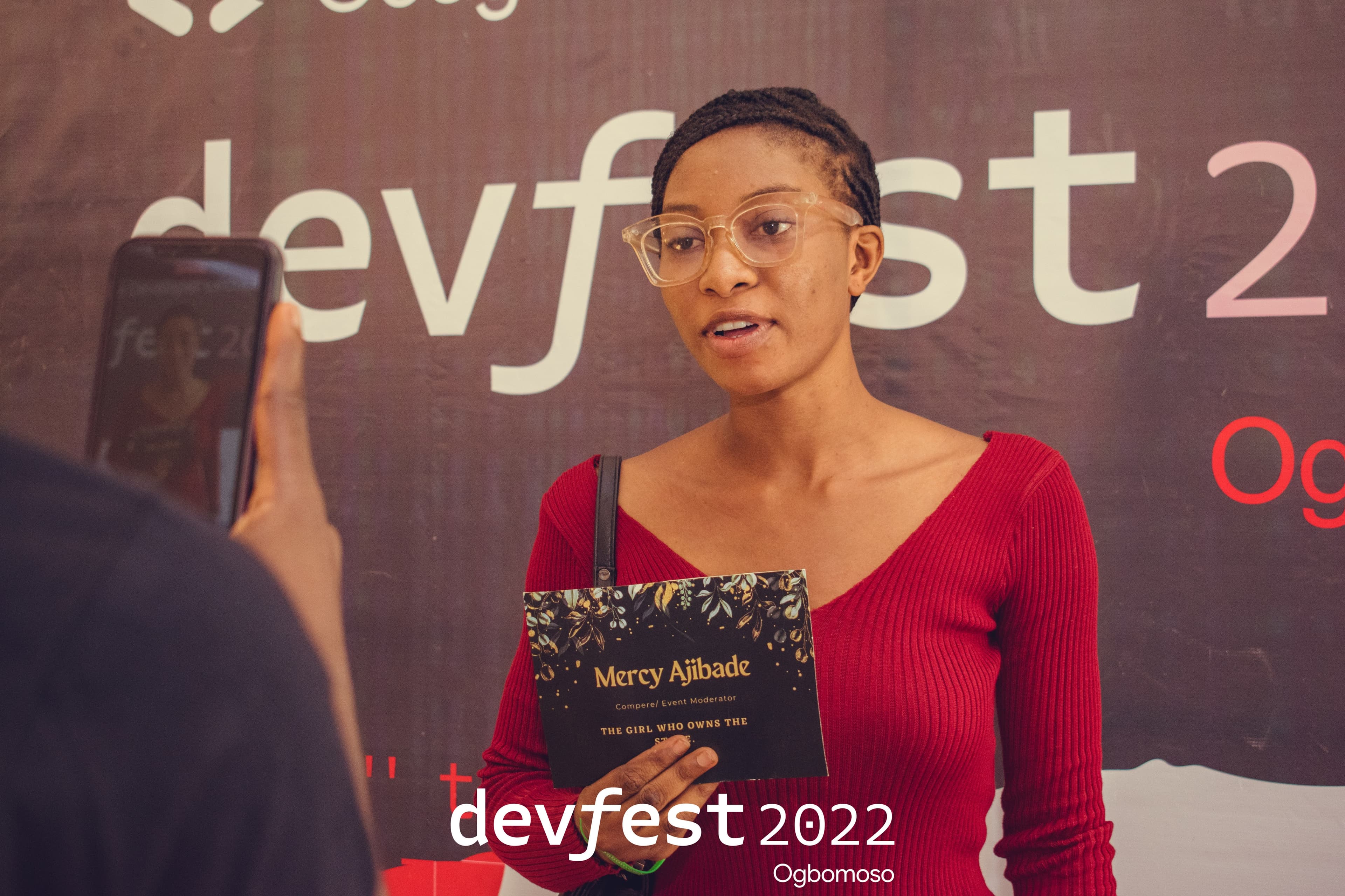 An attendee holding a card while being recorded on a phone at DevFest Ogbomoso 2022