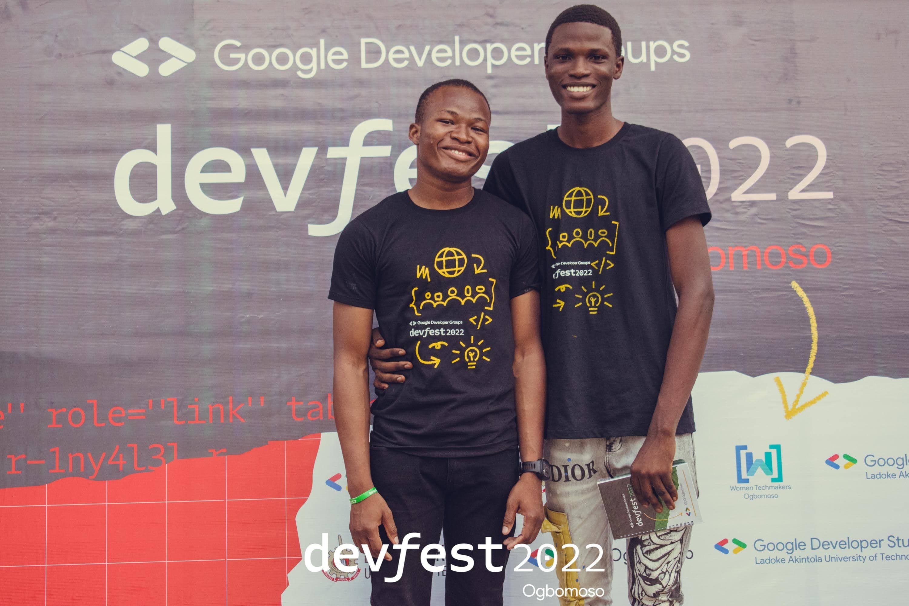Two attendees posing at the backdrop at DevFest Ogbomoso 2022