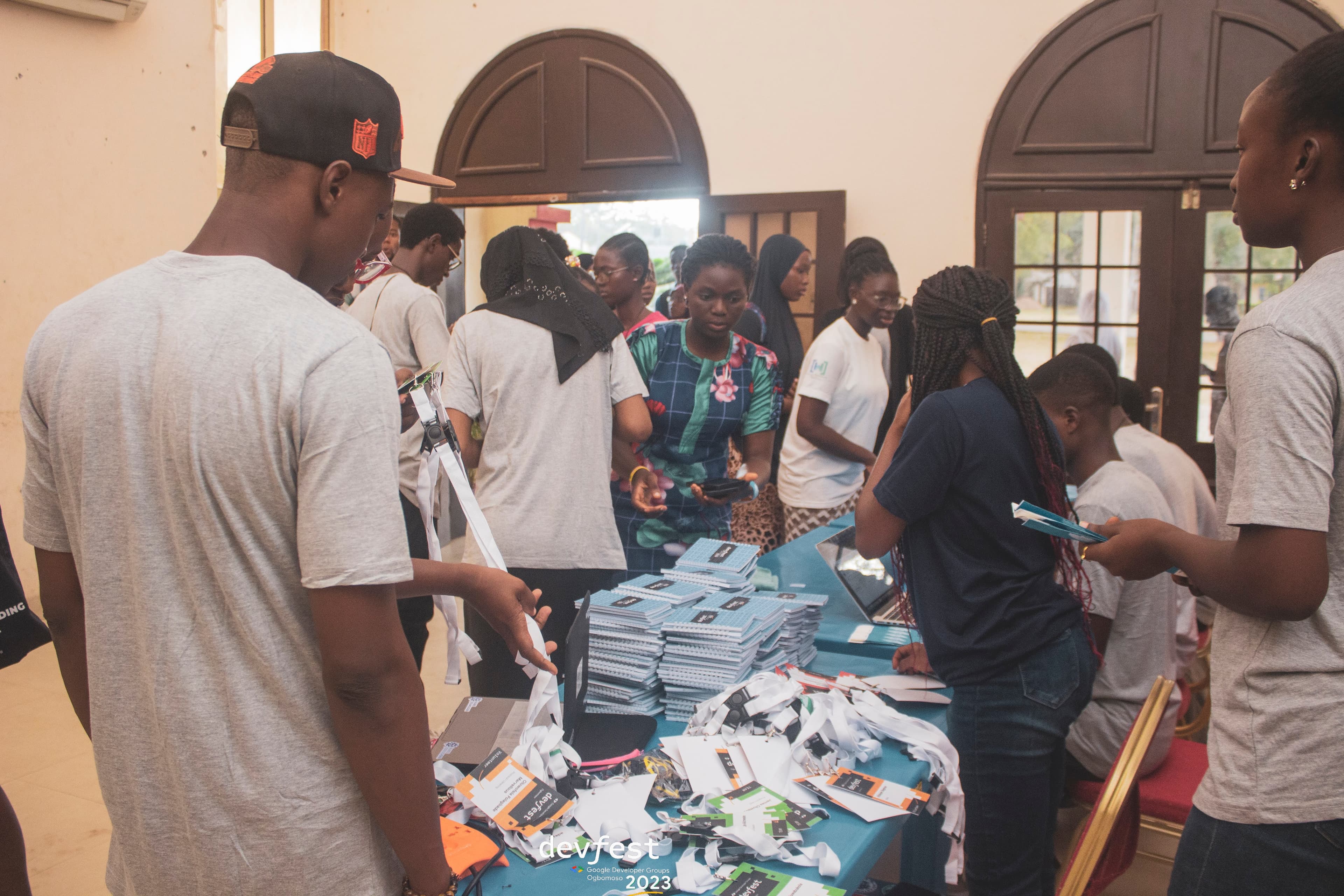 Attendees around a table of lanyards and notebooks at DevFest Ogbomoso 2023