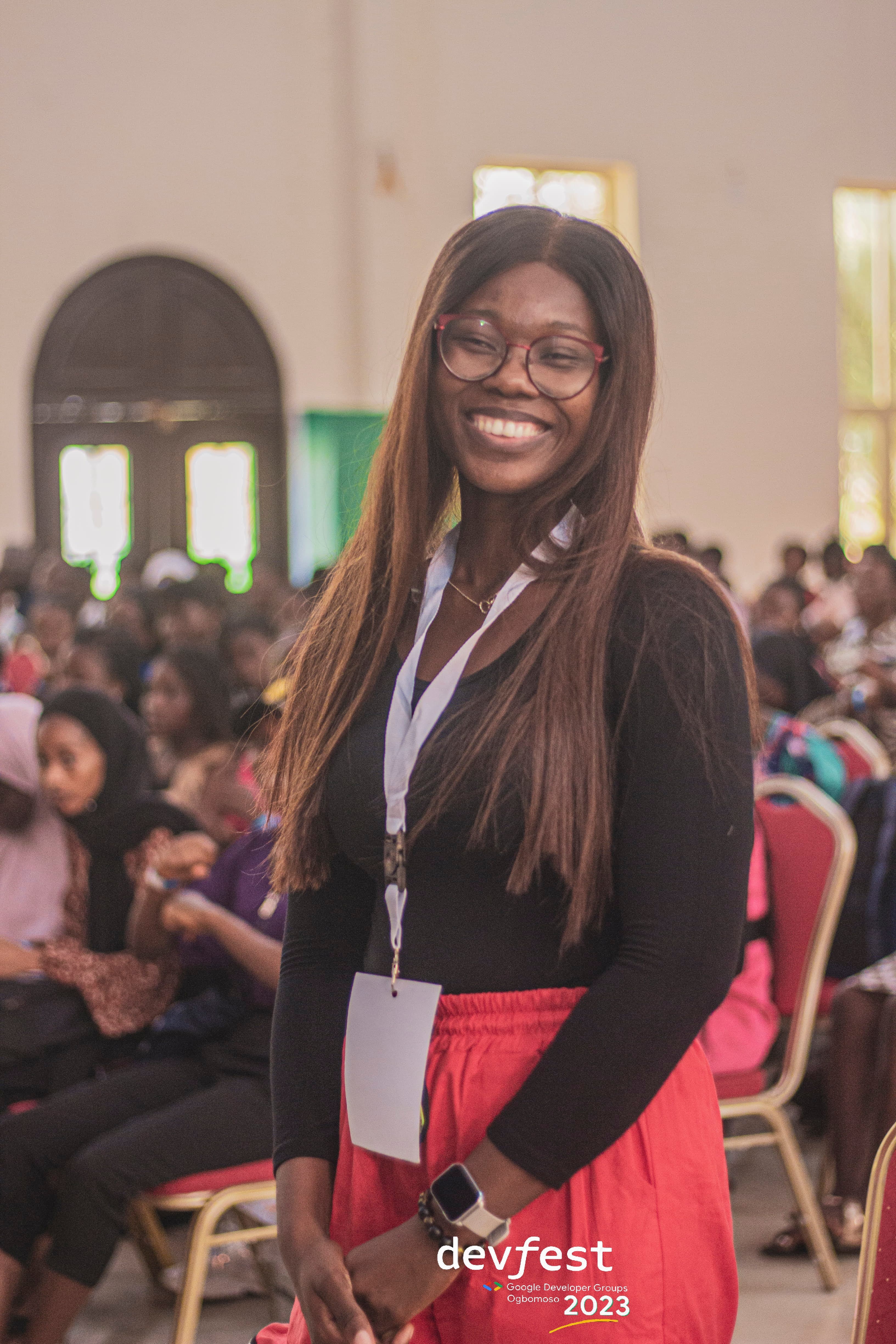 A smiling attendee standing in front of the seated audience at DevFest Ogbomoso 2023