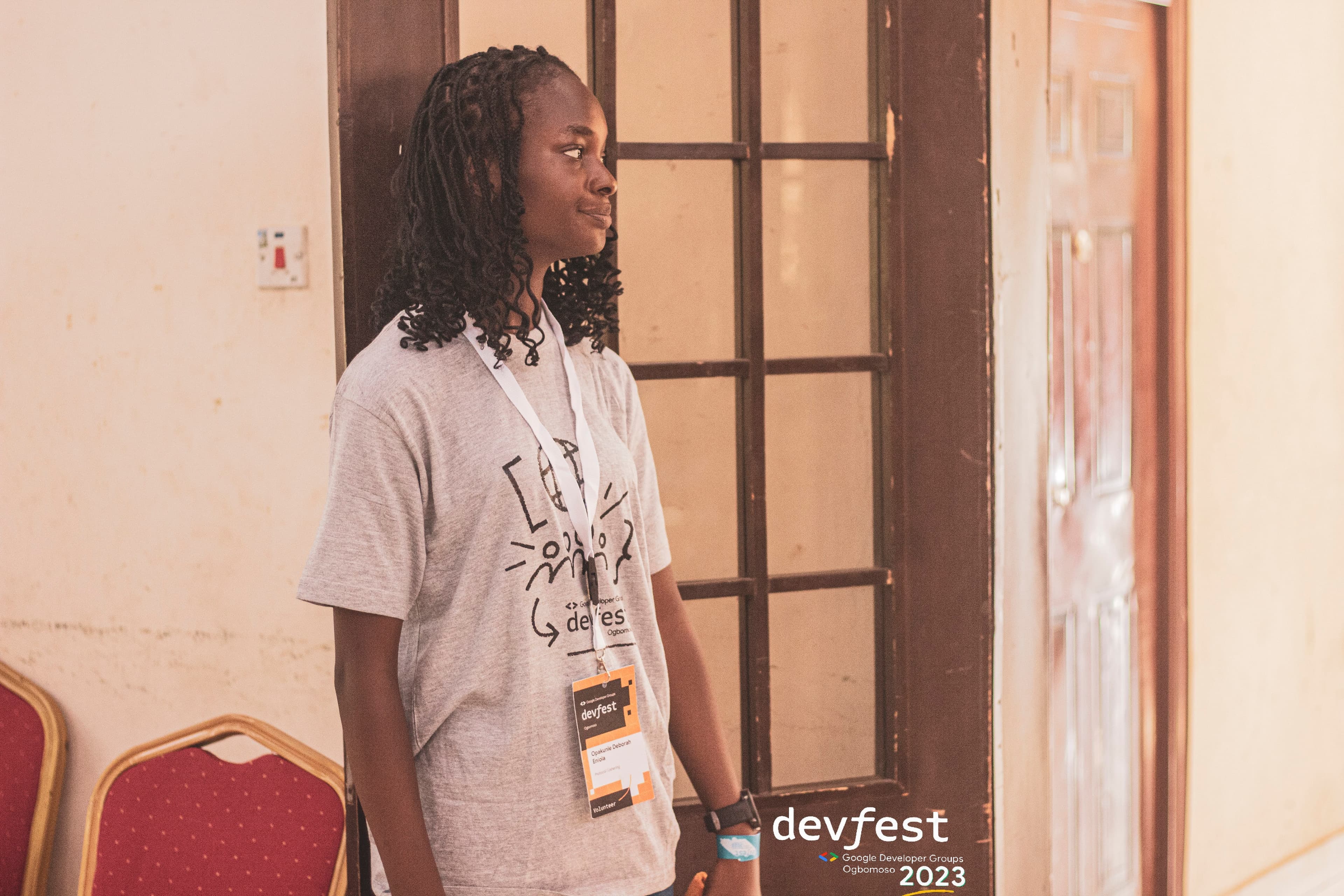 An attendee with a conference badge standing by a window at DevFest Ogbomoso 2023
