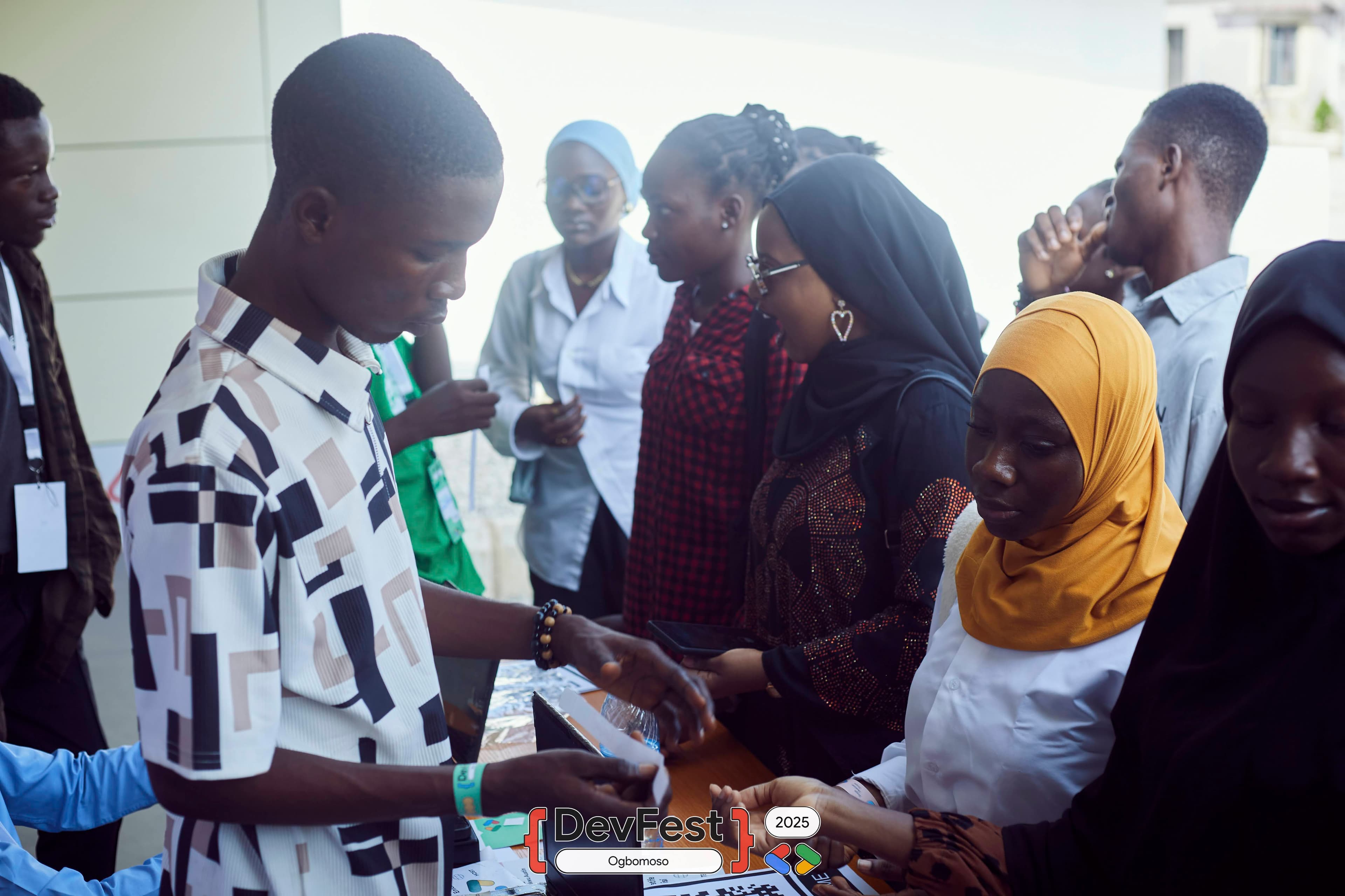Attendees gathered around a table with printed cards at DevFest Ogbomoso 2025