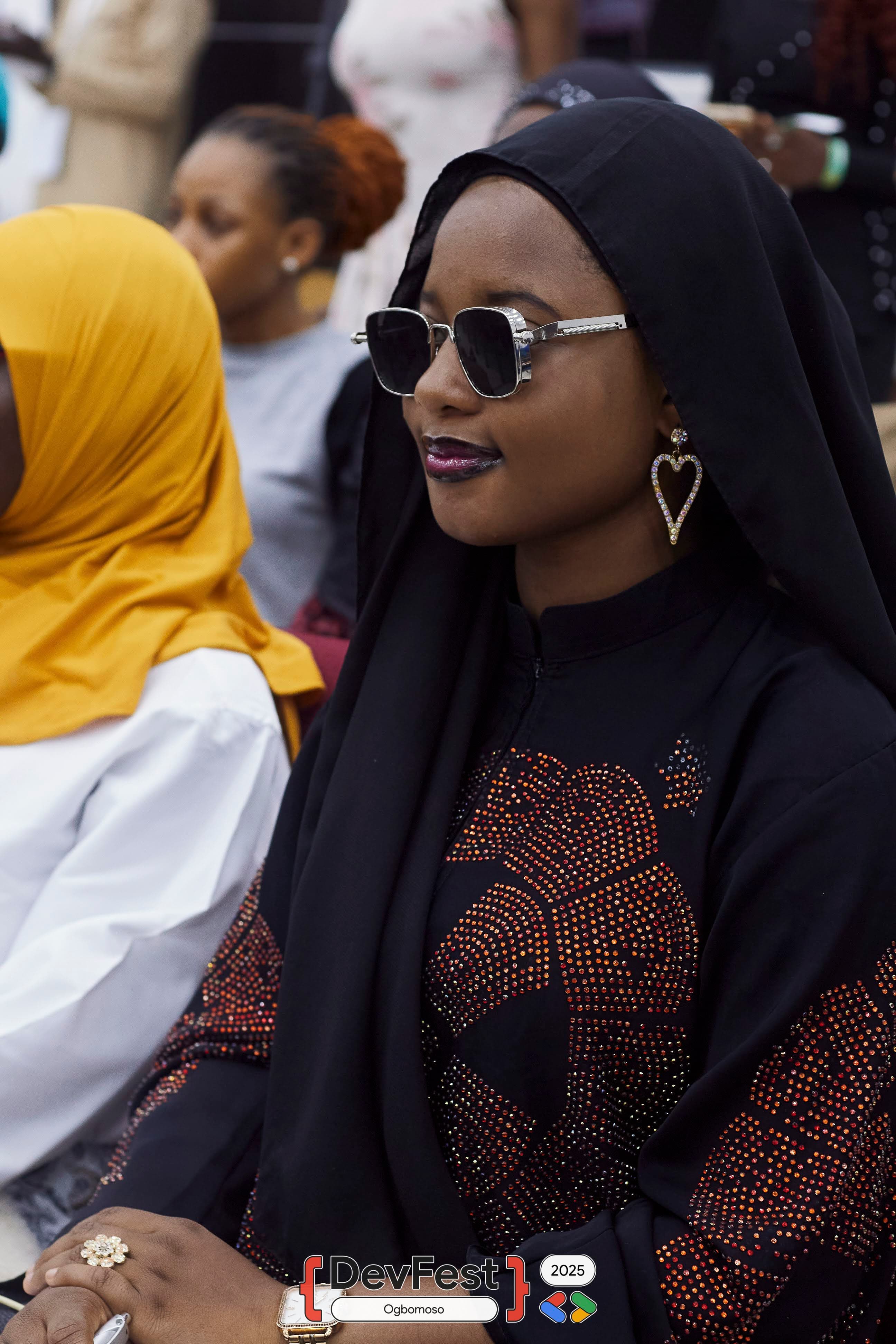 An attendee in sunglasses seated in the audience at DevFest Ogbomoso 2025