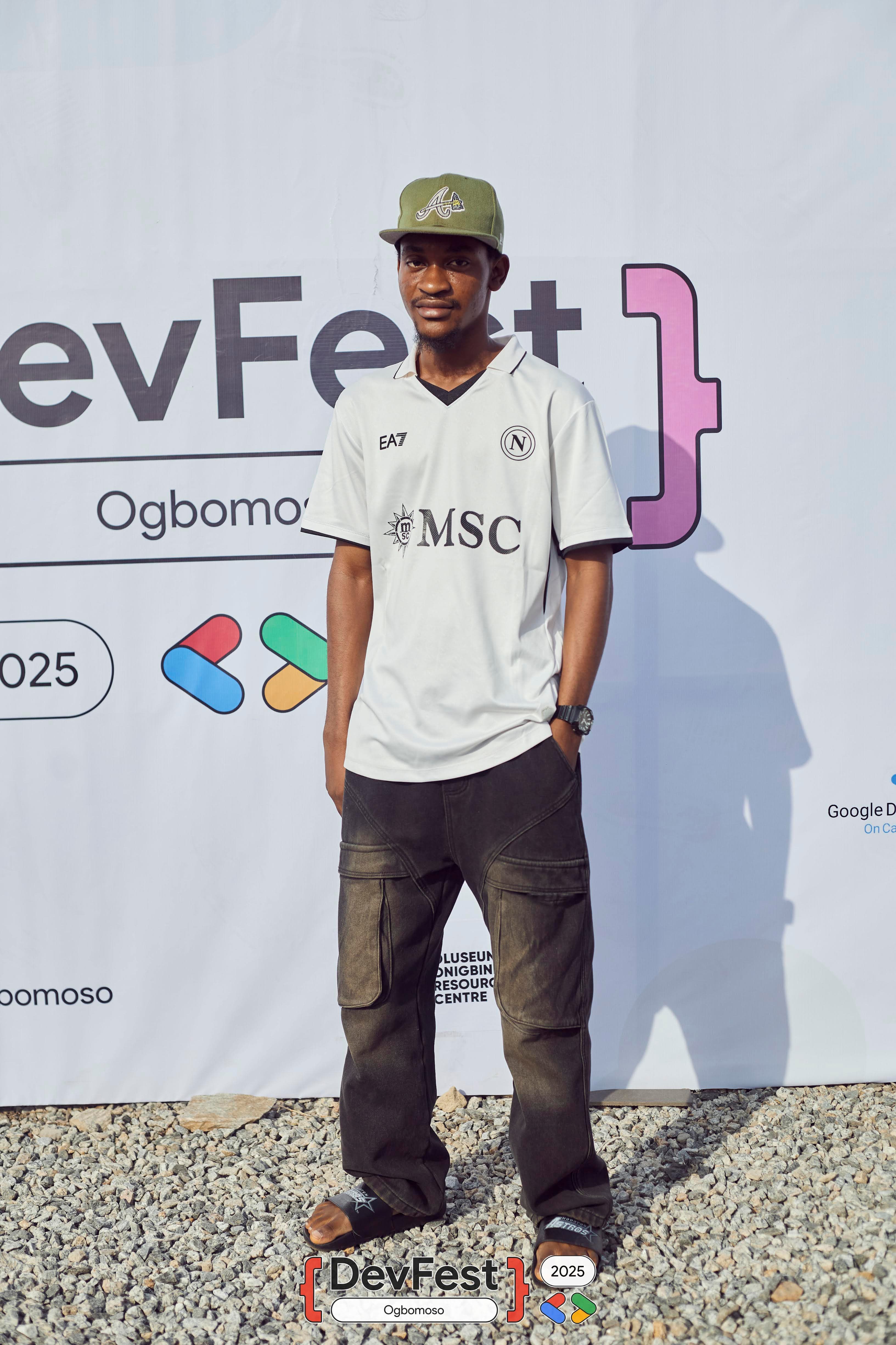 An attendee posing in front of the DevFest banner at DevFest Ogbomoso 2025